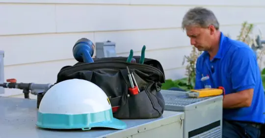 Air conditioner repairman working on an outdoor unit