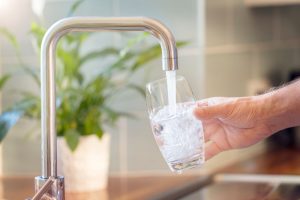 person filling a glass of water