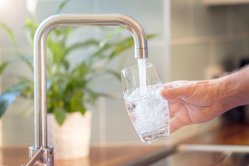 person filling a glass of water